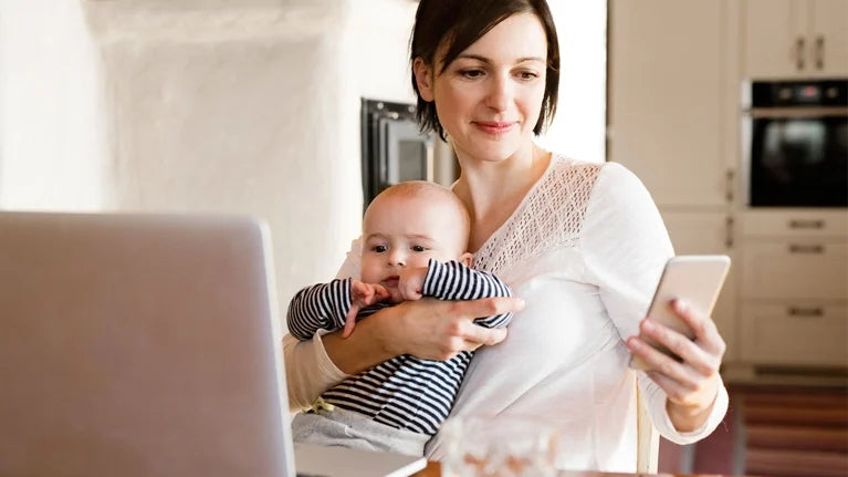 parent holding phone while baby watches closely at home